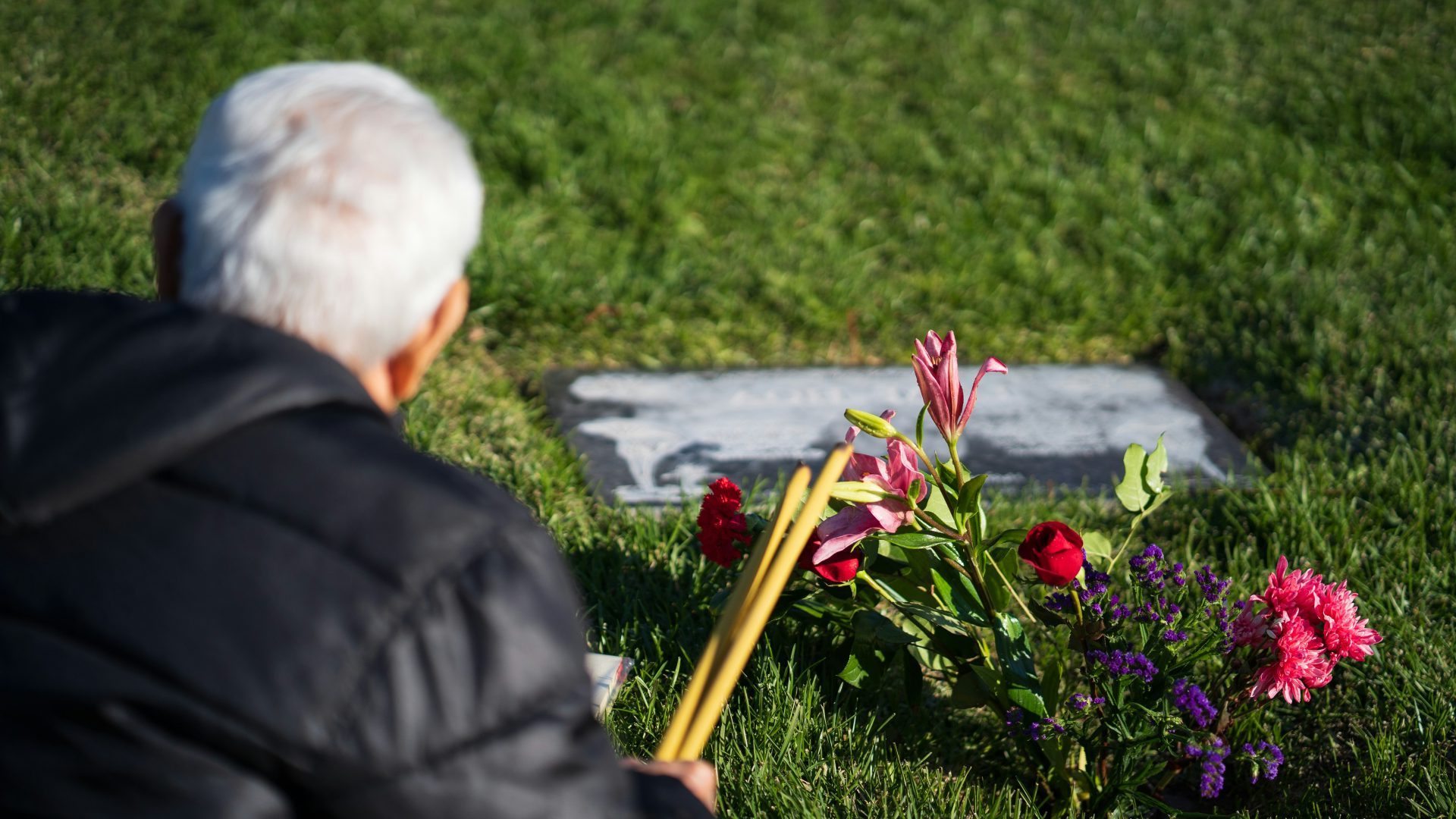 a man sitting in the grass next to flowers